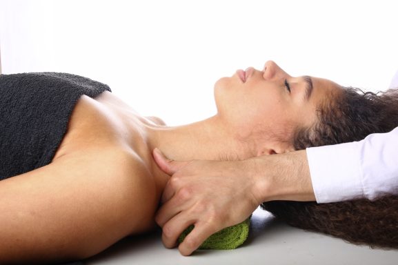 Une femme allongée reçoit un massage relaxant au niveau du cou.